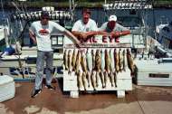 Charter group stands behind the board, loaded up with trophy fish.