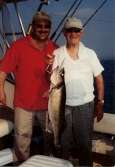 Man in red shirt and older gentleman hold up large trophy walleye.