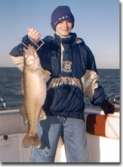 Kid with jacket and hat holds up nice fish.