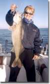 TWoman poses with her catch on the back of the charter boat.